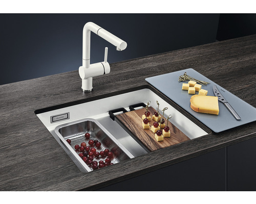 Küchenspüle mit Armatur, Schneidebrett und Lebensmitteln auf einer Arbeitsplatte