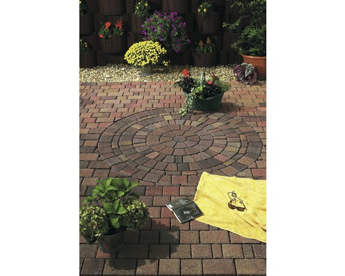 Garten mit Pflastersteinen in Kreisform, Handtuch und Buch