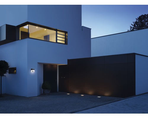 Modernes Haus mit Hausnummerleuchte, Bodeneinbaustrahlern und beleuchtetem Fenster