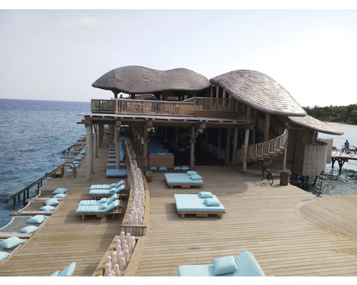 Holzgebäude mit Liegeflächen auf einer Terrasse über dem Wasser