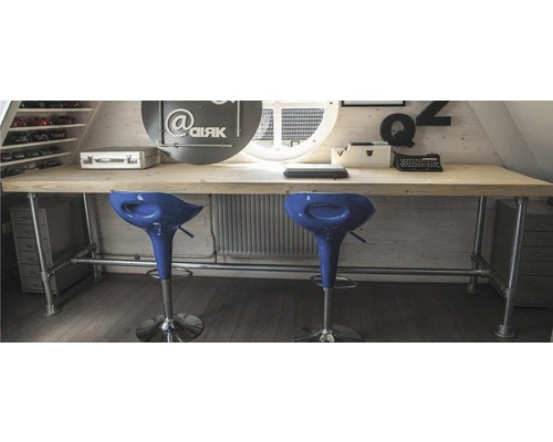 Grenier lumineux avec bureau en bois, structure tubulaire et deux tabourets de bar.