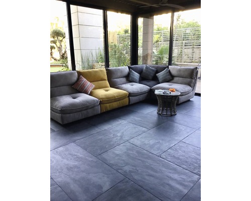 Helles Wohnzimmer mit Ecksofa, Couchtisch und Fliesenboden