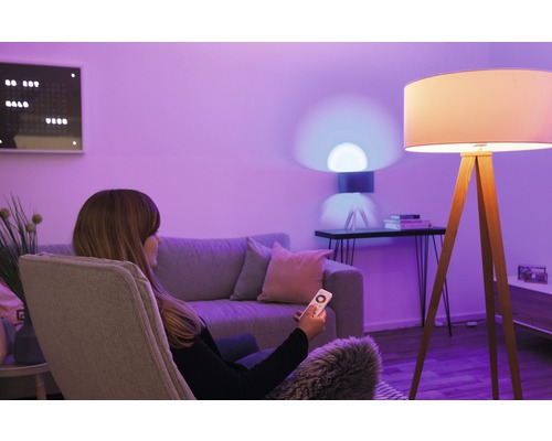 Femme avec télécommande dans un salon avec lampadaire et lampe de table.