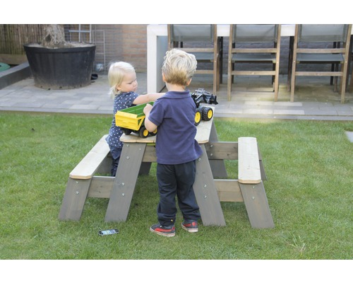 Kinder spielen an einer grauen Kindersitzgruppe im Garten.
