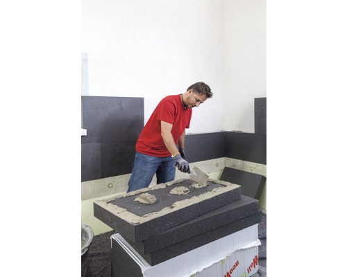 Un artisan applique de la colle sur un panneau isolant