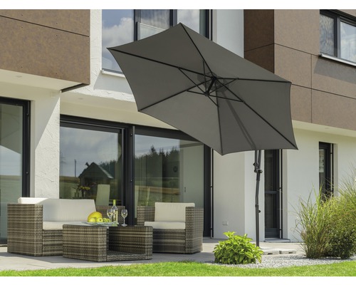 Scène avec un salon de jardin en rotin sous un parasol rectangulaire dans le jardin