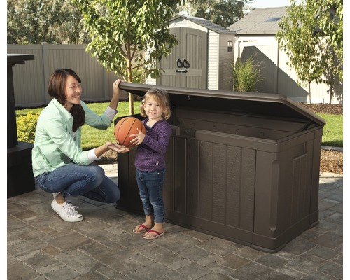 Photo d''une femme et d''un enfant devant un coffre de rangement extérieur marron dans le jardin.