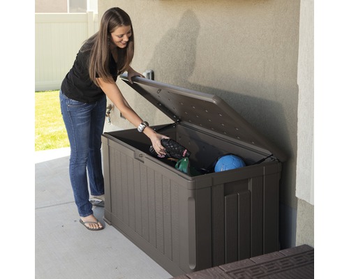 Femme ouvrant un coffre de jardin marron pour ranger des outils de jardin