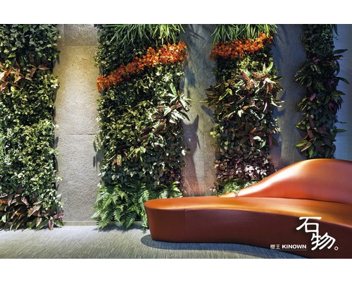 Wandgestaltung mit künstlichen Pflanzen und einer geschwungenen Bank