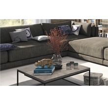 Wohnzimmerszene mit großem Ecksofa, Couchtisch mit Dekorationen und Kissen auf dem Sofa.