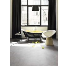 Modernes Badezimmer mit freistehender Badewanne, Sessel und Stehlampe vor einem Fenster.