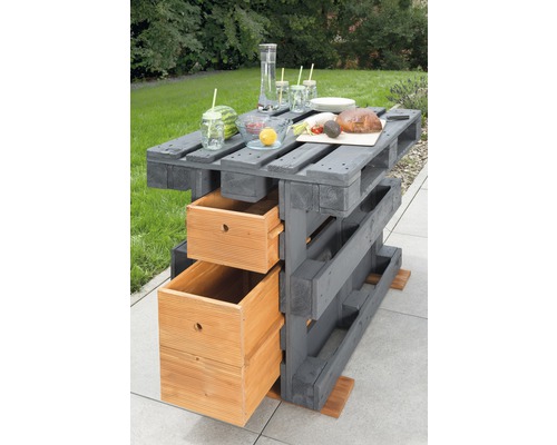 Bar en palettes avec deux tiroirs, décoration de table et scène de jardin en arrière-plan.