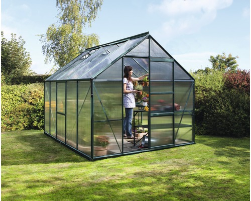 Gewächshaus mit Frau und Pflanzen im Garten.