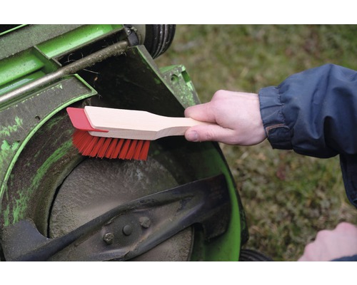 Nettoyage d''une tondeuse à gazon avec une brosse de nettoyage