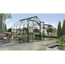 Ein Gewächshaus mit Glaswänden und einem dunklen Rahmen steht im Garten.