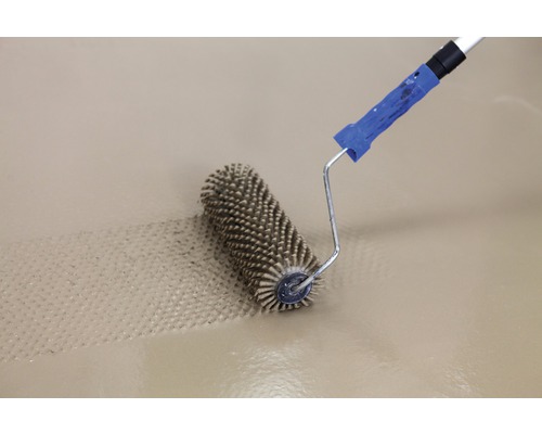 Rouleau à pointes travaillant sur une surface.
