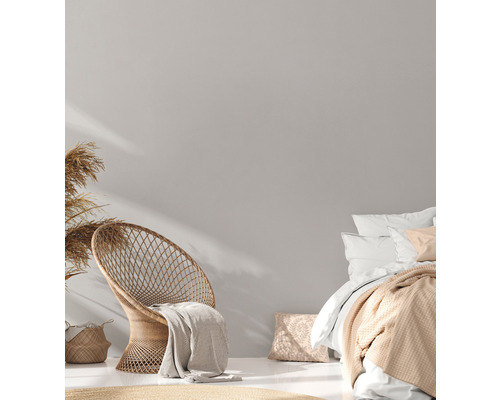 Chambre lumineuse avec fauteuil en rotin et linge de lit