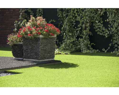 Espace jardin avec gazon synthétique, bacs à fleurs en pierre et lierre