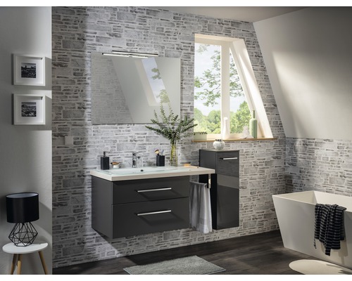 Salle de bains moderne avec meuble-lavabo, miroir, éclairage et baignoire devant un mur en pierre