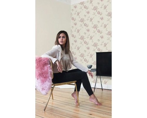 Scène avec une femme assise sur une chaise dans une pièce avec du papier peint floral.