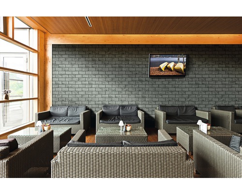 Modernes Interieur mit Rattansitzgruppe, Ziegelwand und Fernseher.