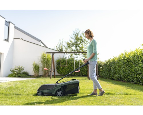 Une femme utilise une tondeuse à gazon dans le jardin