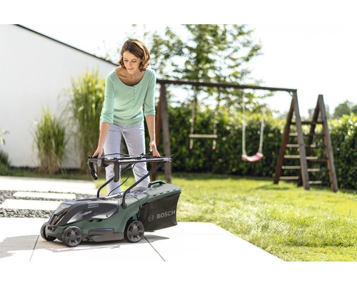 Femme préparant une tondeuse à gazon Bosch dans le jardin