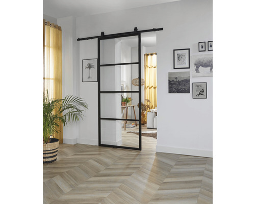 Intérieur avec porte coulissante en verre avec cadre noir et plancher en bois à chevrons