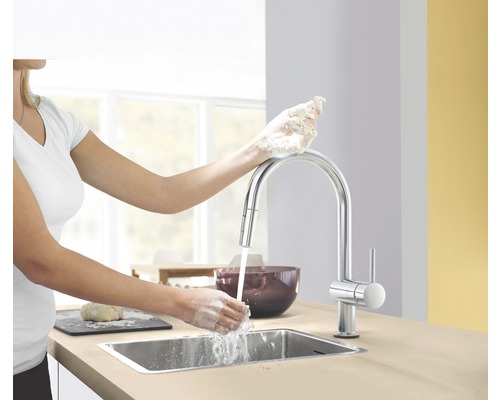 Une femme se lave les mains à un évier avec un mitigeur monocommande dans une cuisine.