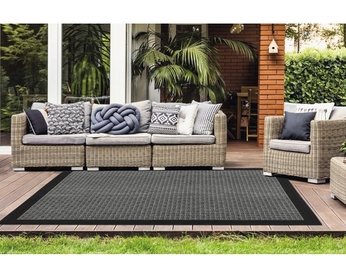 Terrasse avec meubles en rotin et tapis gris