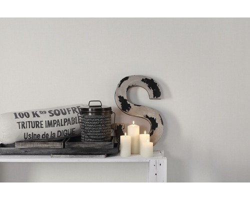 Scène décorative avec coussin, boîte, bougies et un S sur une étagère