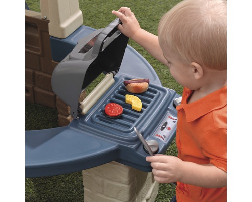 Kind spielt mit Spielzeuggrill mit Spielzeugessen