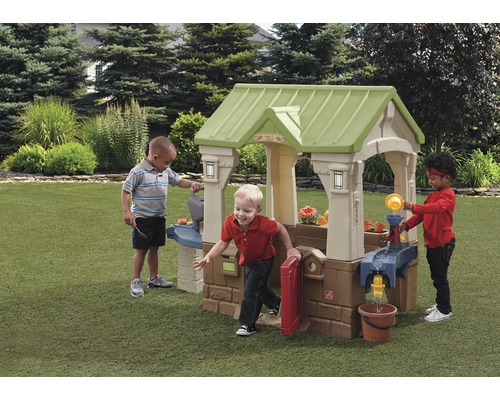 Drei Kinder spielen mit einem Step2 Spielhaus im Garten.