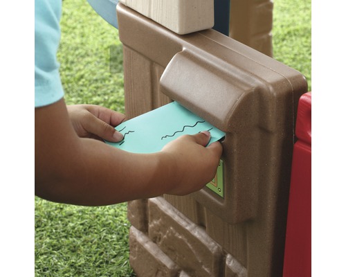 Ein Kind steckt einen Brief in den Briefkasten eines Spielhauses