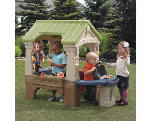 Spielhaus mit Grill und spielenden Kindern im Garten