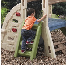Un enfant grimpe sur une combinaison de jeux d''extérieur avec mur d''escalade et toboggan.