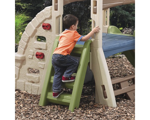 Ein Kind klettert auf einer Spielplatzkombination mit Kletterwand und Rutsche.