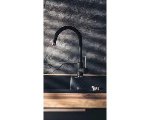 Robinet de cuisine noir avec évier devant un mur de pierre