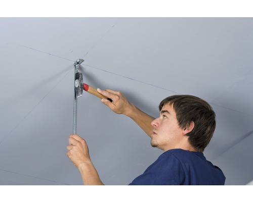Mann befestigt eine Deckenkonstruktion mit Hammer und Metallprofil