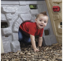 Un enfant rampe dans un tunnel de jeu avec mur d''escalade dans le jardin.