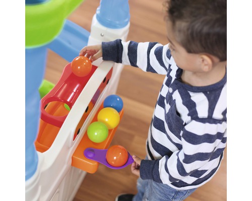 Un enfant joue avec un circuit à billes avec des balles colorées.