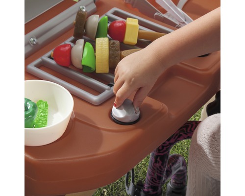 Spielküche mit Grillfunktion und Spielzeugessen, bedient von einem Kind