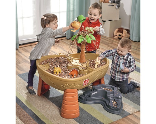 Drei Kinder spielen mit einem Step2 Dino Sand- und Wassertisch mit Zubehör und Dinos im Innenbereich.