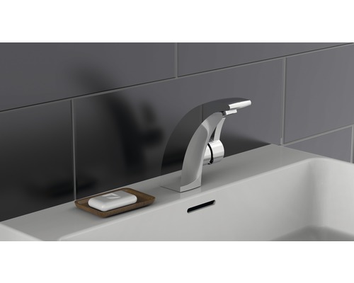 Un robinet et un savon dans un plat sont placés sur un lavabo.