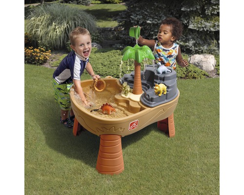 Kinder spielen mit einem Dinosaurier-Wasserspieltisch im Garten.