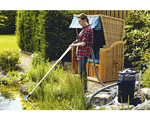 Femme nettoie un bassin avec un aspirateur de bassin à côté d''une chaise de plage