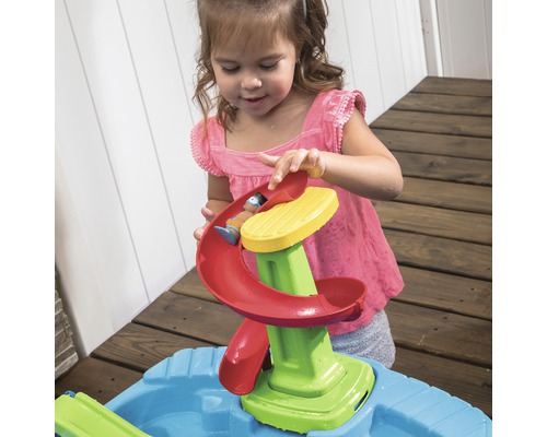 Fille jouant avec un toboggan à eau sur une table de sable et d''eau