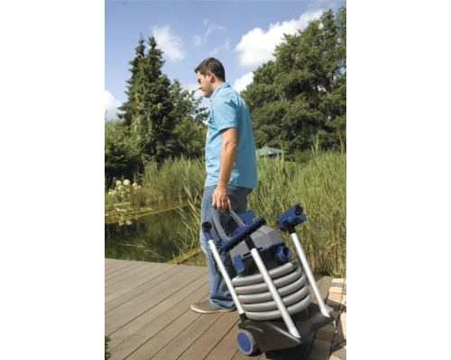 Un homme transporte un aspirateur de bassin au bord d''un étang