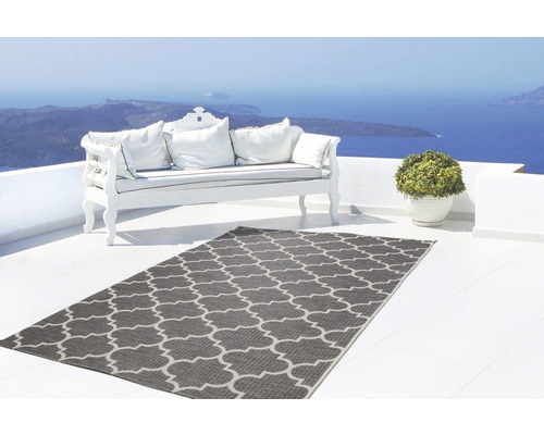 Szene mit grauem Außenteppich mit geometrischem Muster auf einer Terrasse mit Sofa und Meerblick