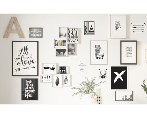 Wanddekoration mit verschiedenen Bildern, Postern und einem Holzbuchstaben A an einer weißen Wand.
